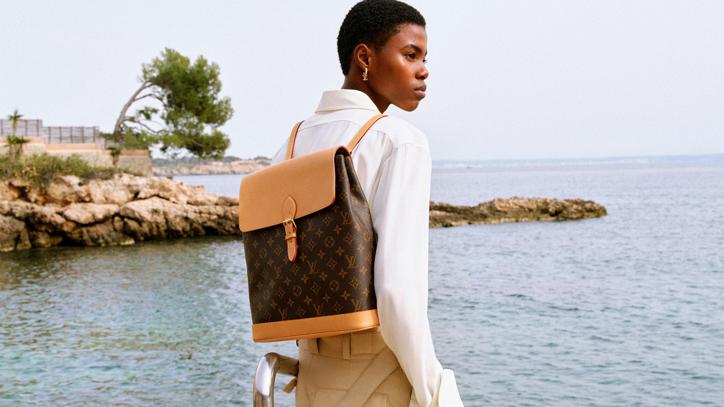 Person with Louis Vuitton backpack by the sea